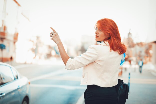 Mujer de negocios parada en la calle llamando a Taxi.