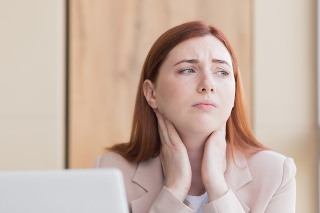 Mujer de negocios pelirroja con dolor de muelas severo y dolor de cabeza en el exceso de trabajo de la computadora