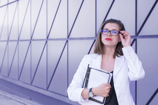 Mujer de negocios de pie contra el telón de fondo de una pared púrpura muy peri color del año 2022 de moda