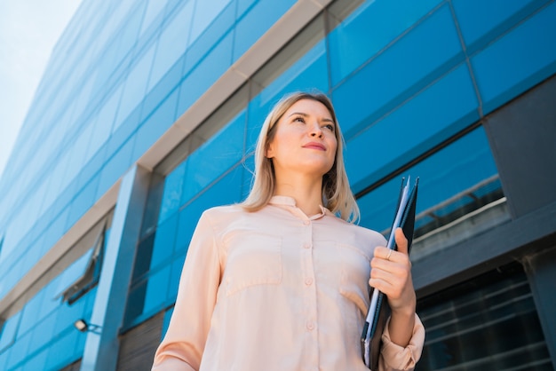 Mujer de negocios de pie fuera de los edificios de oficinas.