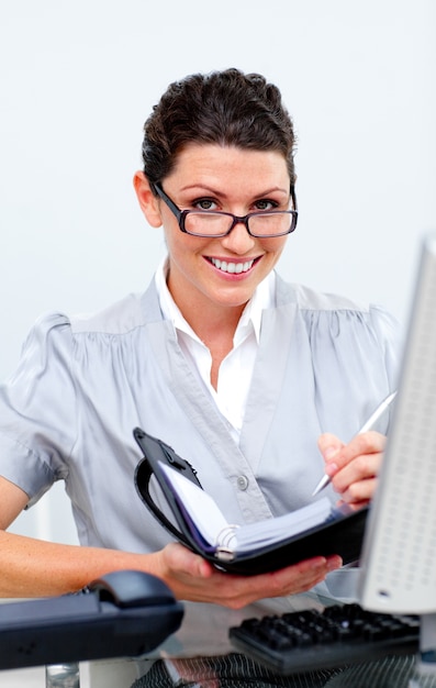 Foto mujer de negocios positivo escribiendo en su agenda