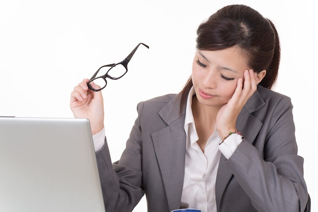 Mujer de negocios preocupada que trabaja con la computadora portátil en el escritorio contra el fondo blanco.