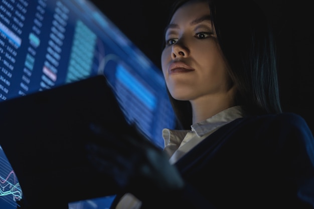 Foto la mujer de negocios que sostiene la tableta en la oficina oscura