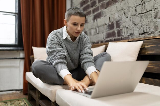 Mujer de negocios que trabaja desde casa sentada con una laptop en el sofá