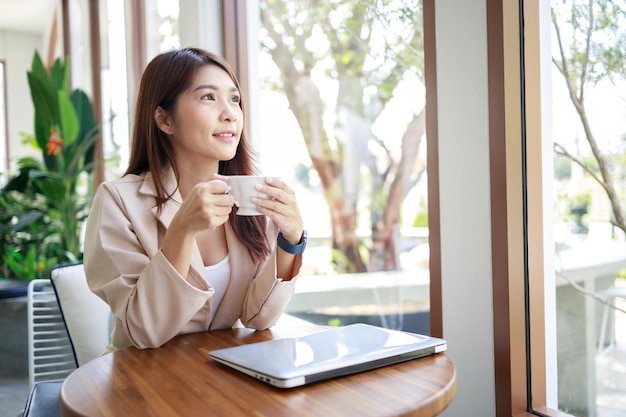 Mujer de negocios que trabaja con una computadora portátil en la cafetería