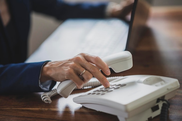 Mujer de negocios que trabaja en una computadora portátil marcando un número de teléfono