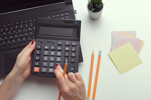 Mujer de negocios que trabaja con datos financieros mano usando calculadora