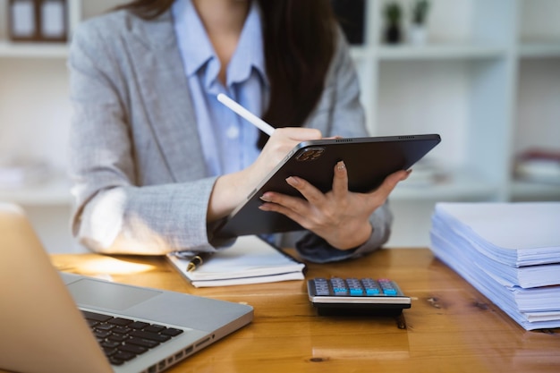 Foto mujer de negocios que trabaja con documentos de negocios de tableta y calculadora y computadora portátil