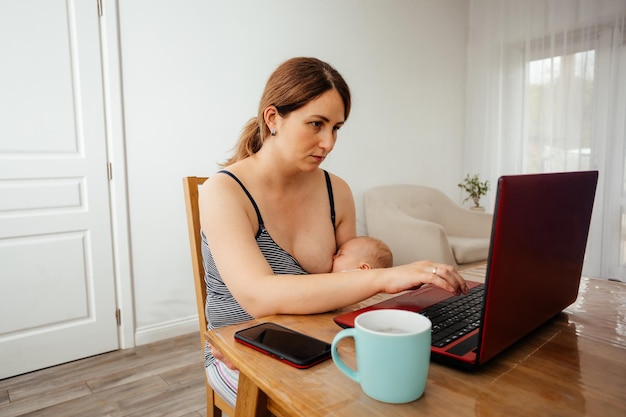 Mujer de negocios que trabaja de forma remota con un bebé recién nacido dormido