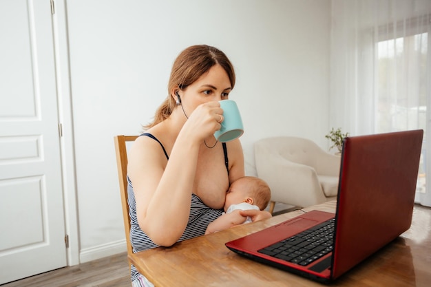 Mujer de negocios que trabaja de forma remota con un bebé recién nacido dormido