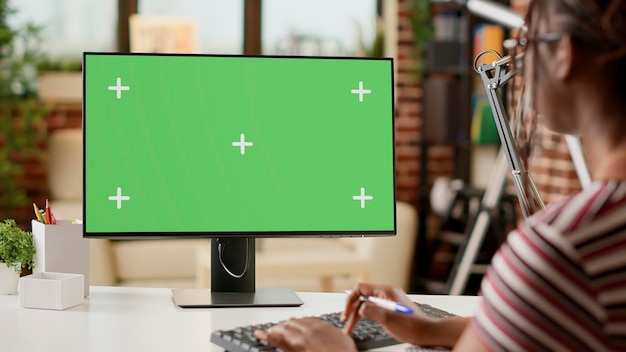 Mujer de negocios que trabaja de forma remota con pantalla verde en la computadora, usando la plantilla de clave de croma en casa. Hacer trabajo remoto con pantalla de maqueta aislada, fondo en blanco y espacio de copia en el monitor.