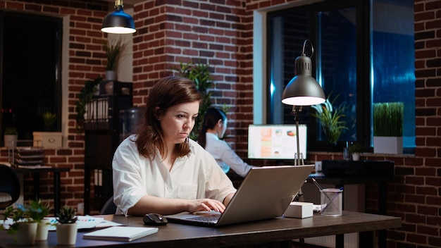 Mujer de negocios que trabaja horas extras para un proyecto de la empresa haciendo tareas en la oficina