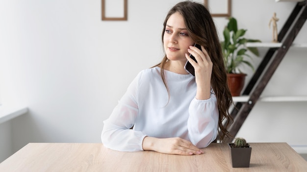 Foto mujer de negocios que trabaja en la oficina se comunica por teléfono celular con un cliente llamadas móviles en casa una llamada al dispositivo y una niña sentada en la mesa