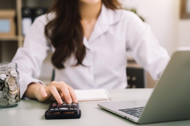 Mujer de negocios que trabaja en la oficina de escritorio usando una calculadora para calcular