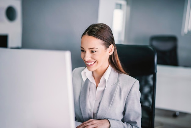 Una mujer de negocios que trabaja en la oficina y sonríe a la computadora