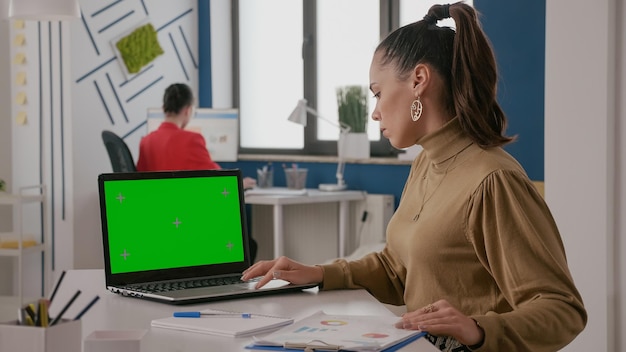 Foto mujer de negocios que trabaja con pantalla verde en la computadora portátil, computadora con fondo de maqueta y plantilla de espacio de copia aislada en clave de croma. trabajador con maqueta de clave cromática en pantalla.