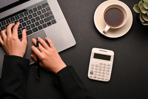 Mujer de negocios que trabaja en su escritorio de oficina escribiendo en la vista superior de la computadora portátil