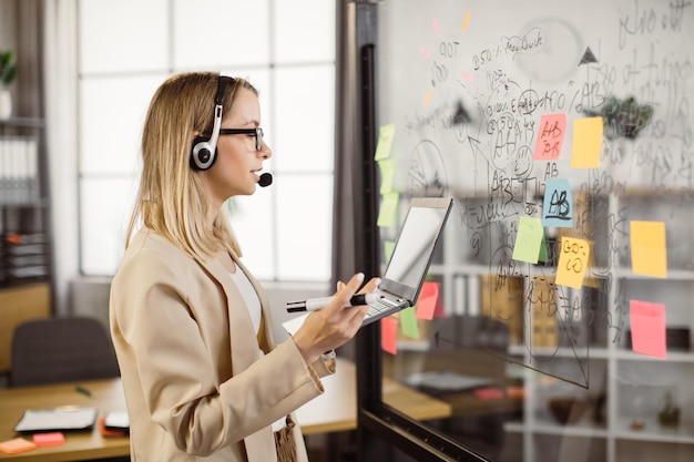 Mujer de negocios que usa auriculares y computadora portátil para videollamadas