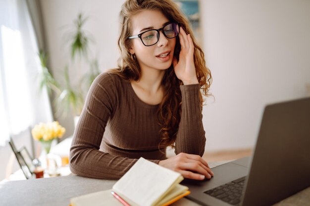 Mujer de negocios que usa una computadora portátil con gafas mientras está sentada en el lugar de trabajo en casa Concepto freelance