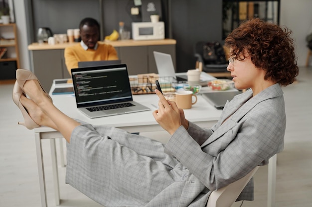 Mujer de negocios que usa un teléfono inteligente durante el descanso en la oficina