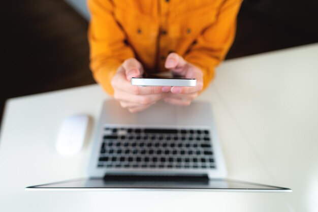 Foto mujer de negocios que usa un teléfono inteligente móvil y trabaja en una computadora portátil con una tableta digital en la oficina