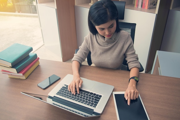 Mujer de negocios que utiliza tecnologías en el escritorio de la oficina