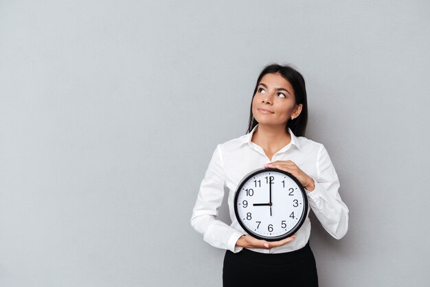 Mujer de negocios con reloj y mirando hacia arriba