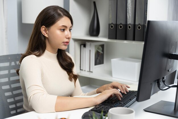 Mujer de negocios de ropa casual buscando informe en la computadora y escribiendo postulado