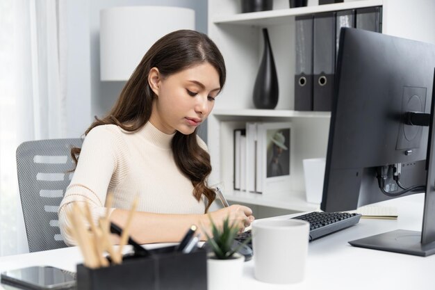 Mujer de negocios de ropa casual buscando informe en la computadora y escribiendo postulado