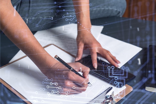 Una mujer de negocios con ropa informal escribiendo algunas ideas usando el teléfono para crear un software innovador para proporcionar un servicio de alta tecnología completamente nuevo Primer plano Gráficos de tecnología de hologramas Concepto del equipo de desarrollo