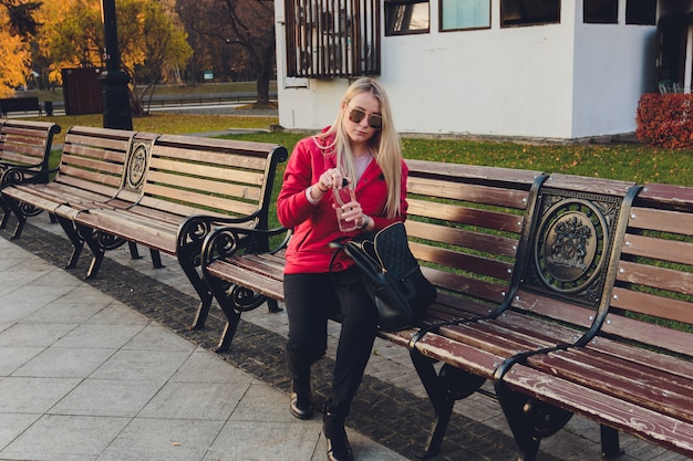 Mujer de negocios rubia joven con bolsa en el parque.