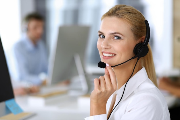 Mujer de negocios rubia usando auriculares para comunicarse