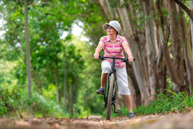 Mujer de negocios senior paseo femenino o bicicleta de montaña para hacer ejercicio saludable en el fin de semana de verano