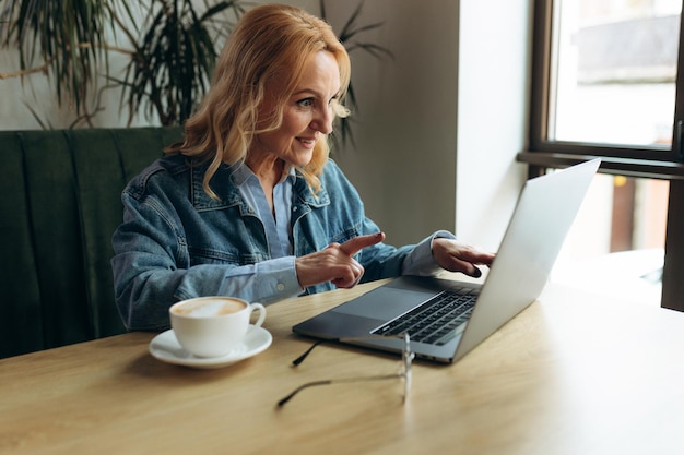 Mujer de negocios senior sentada en una cafetería y trabajando en una computadora portátil Mujer madura en un café usando una computadora portátil