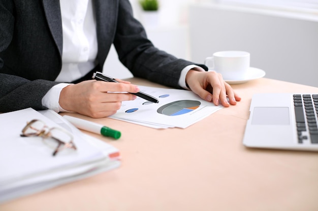 Mujer de negocios sentada en la mesa y examina los resultados financieros.