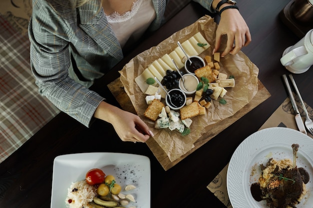 Mujer de negocios sentada en una mesa en un restaurante y sostiene en la mano un plato de queso