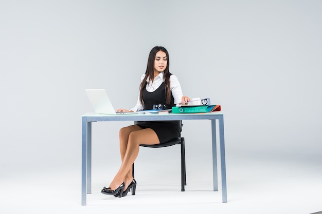 Foto mujer de negocios sentada en la mesa de trabajo con papel aislado en gris