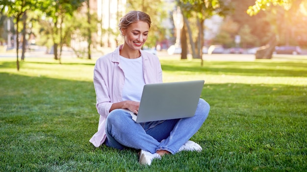 Mujer de negocios sentado en el parque de verano de hierba utilizando equipo portátil Personas de negocios trabajando a distancia. Al aire libre