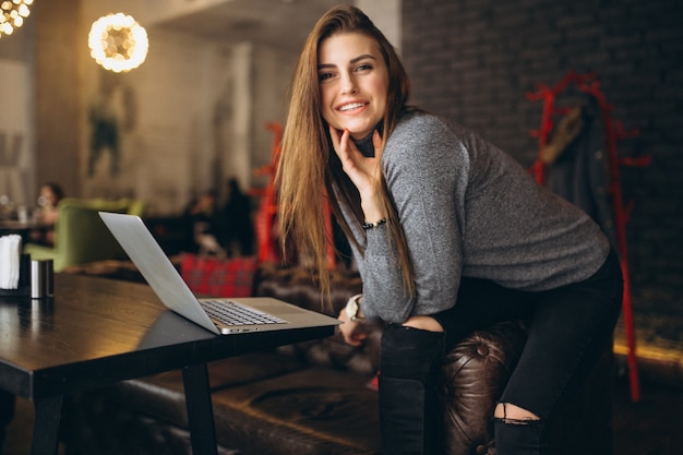 Mujer de negocios sentado en un sofá con la computadora portátil en un café