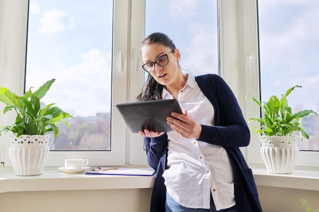 Mujer de negocios seria hablando por videollamada usando tableta digital