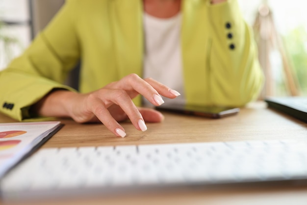 La mujer de negocios se sienta en el escritorio de su oficina con una computadora y un teléfono inteligente y piensa en proyectos comerciales