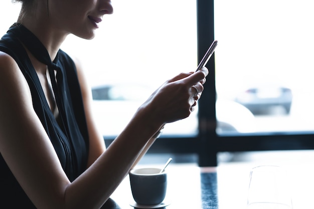 Mujer de negocios con smartphone durante el almuerzo en la cafetería.