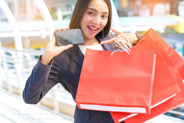 Mujer de negocios con smartphone y bolsas de compras