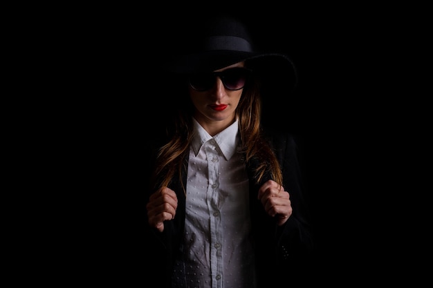 Foto mujer de negocios con un sombrero negro, gafas en un negro.