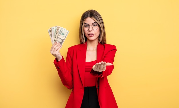 Mujer de negocios sonriendo alegremente con amabilidad y ofreciendo y mostrando un concepto. concepto de billetes de dólar