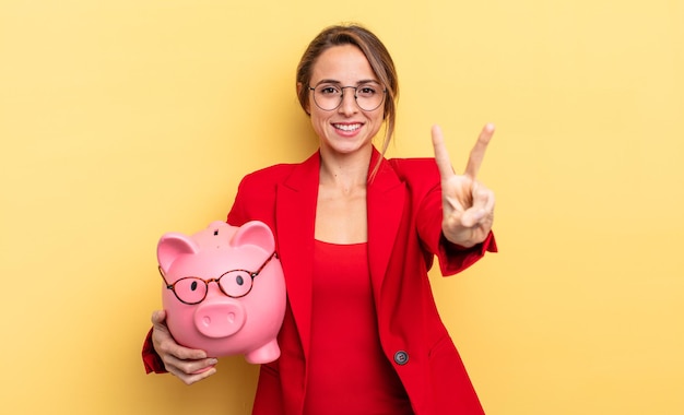 Mujer de negocios sonriendo y luciendo amistosa, mostrando el número dos. concepto de alcancía