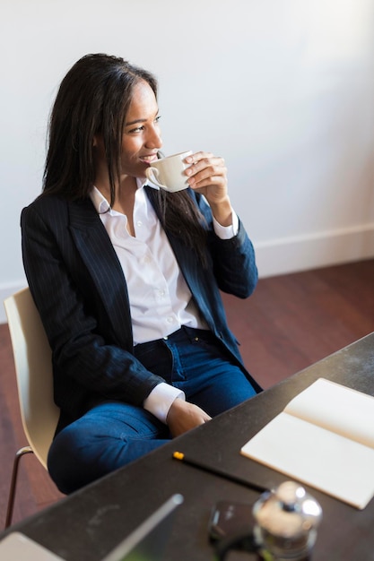 Mujer de negocios sonriente bebiendo café durante una reunión en la oficina