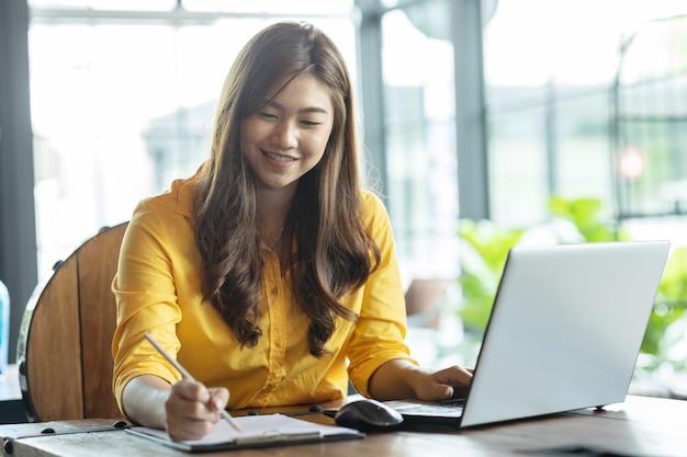 Una mujer de negocios sonriente escribiendo en un documento en la oficina