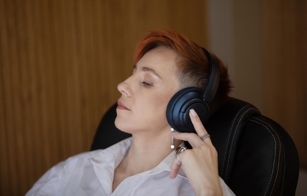 Mujer de negocios sonriente con los ojos cerrados escuchando música en auriculares en la oficina