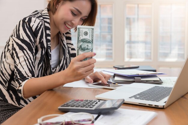 Foto una mujer de negocios sonriente con papel moneda en la oficina